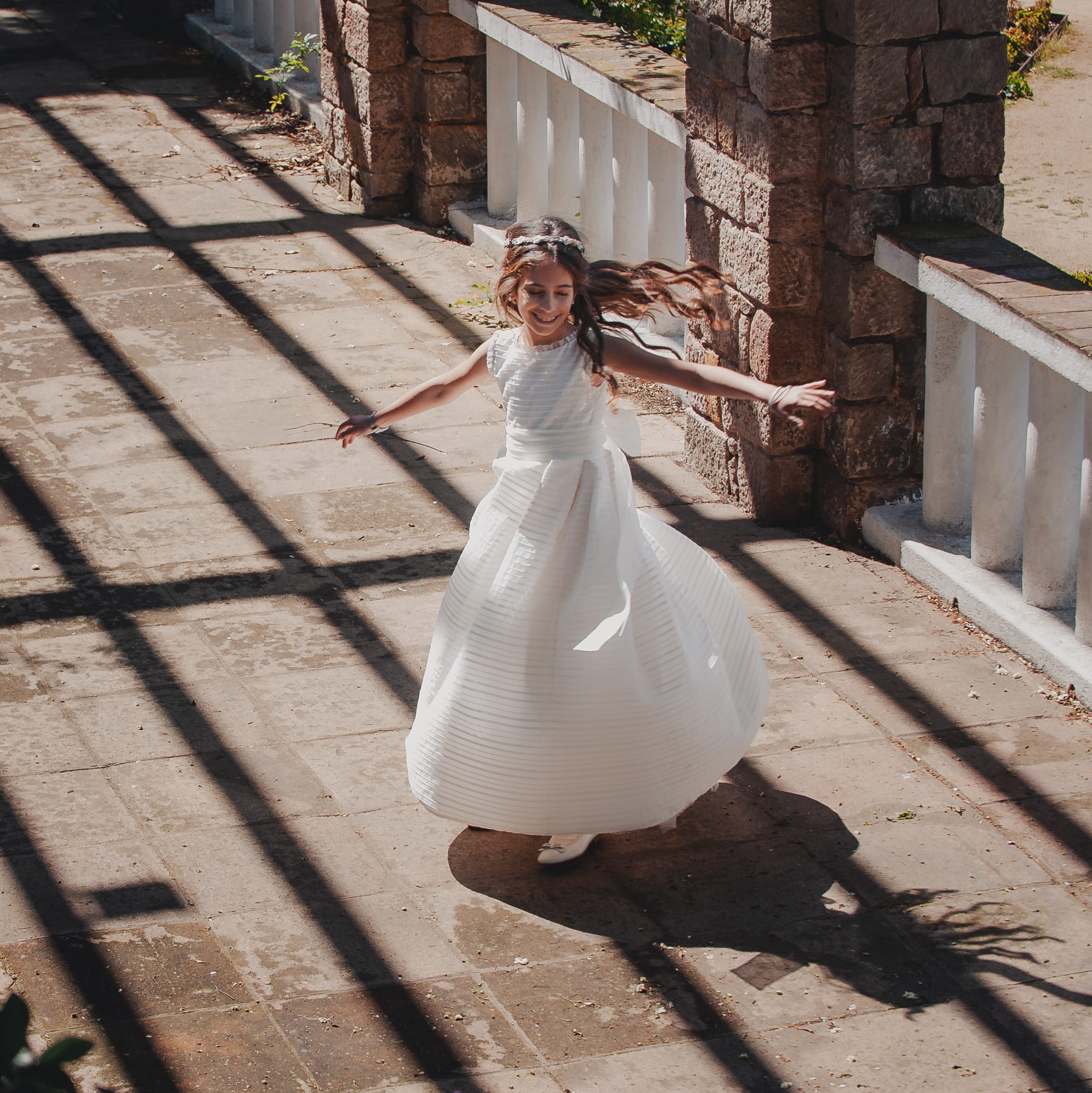 Niña corriendo con vestido de comunión durante una sesión de fotos de comunión natural en Barcelona